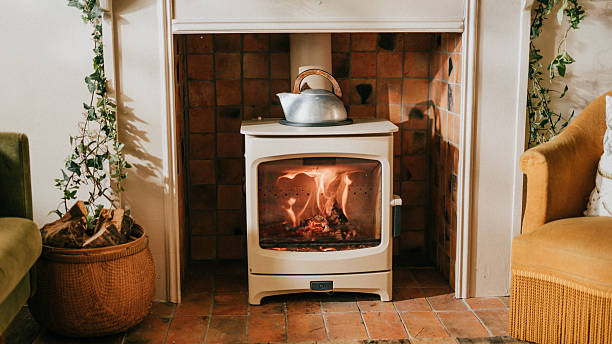 A fireplace with a teapot on top of it. The teapot is silver and the fire is burning brightly. The room is cozy and warm