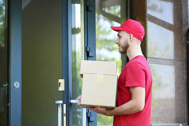 istock Delivery man in red uniform with cardboard boxes 2210253328