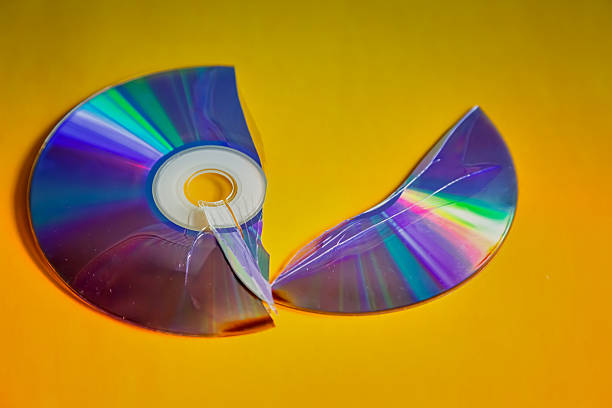 istock Halves of a cracked and broken compact disc on a yellow background, a broken CD disc, damage to an old storage medium, obsolete technology. 2210254571