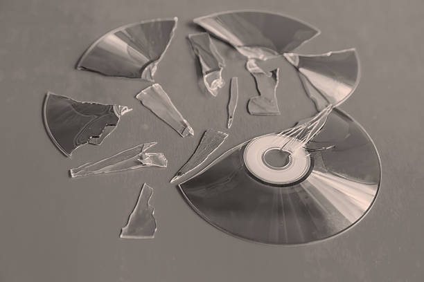 Close-up of blank music CD in mid-air with flying musical notes against light blue background.