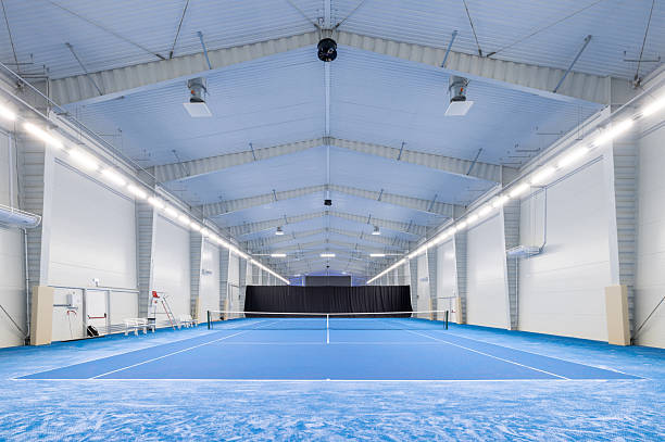 istock Spacious Indoor Tennis Court With Blue Surface and Modern Lighting 2210254716