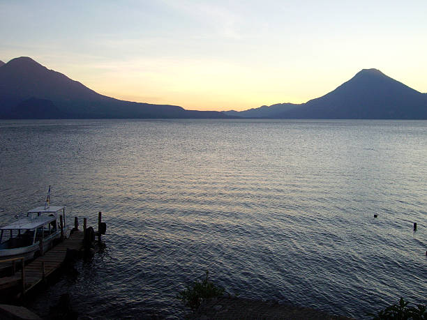 Aerial of a small fisherman village of Panajachel on Lake Atitlan in Guatemala during sunrise, displaying the lake and the boats in the foreground with the houses and streets in the background