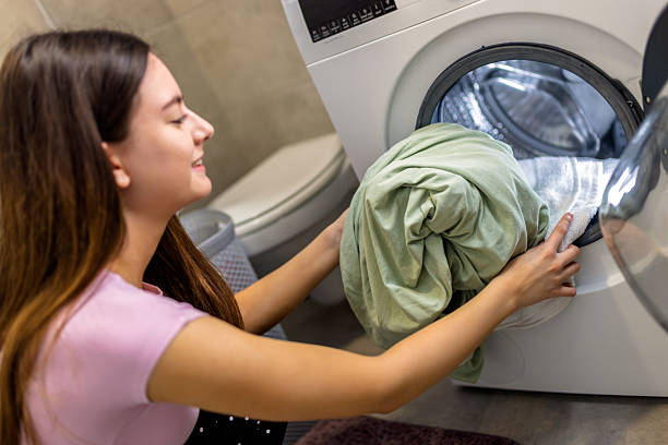 istock Woman puts bedding in the washing machine. 2210260865