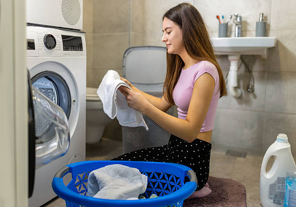 istock Young woman doing housework putting clothes into washing machine. 2210260953