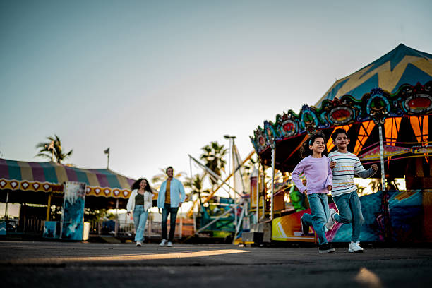 istock Child siblings running on amusement park and parents on background 2210265449