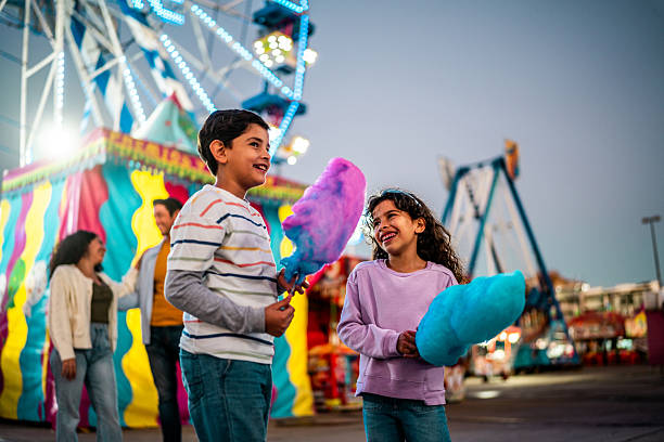 istock Child siblings holding cotton candy at amusement park 2210265510