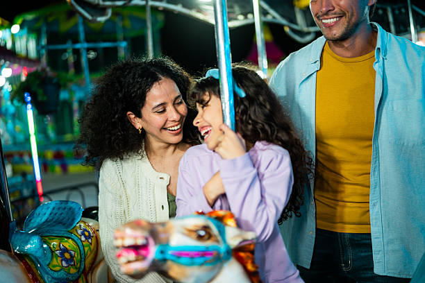 istock Mother and daughter talking on carousel at amusement park 2210266078