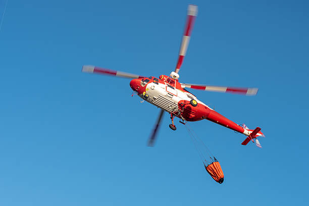 istock Red helicopter flying above with empty Bambi bucket 2210266633