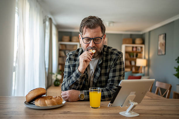 istock Mature man enjoying breakfast and watching tablet at home 2210268527