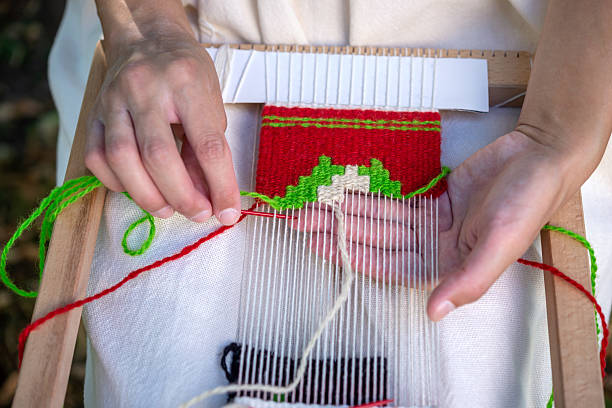 Close-up of a woman weaver's hand using a weaving needle on a hand loom. Selective focus.
