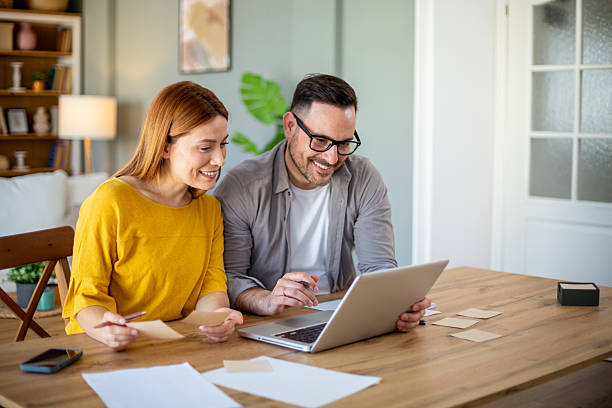 istock Smiling couple doing home finances looking at laptop 2210273650