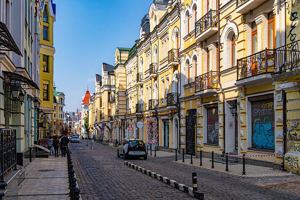 Kyiv, Ukraine - March 23, 2025: Beautiful old houses in the historic Podil district in Kyiv, Andriivskyj descent. Sunny spring day and people walking on the street