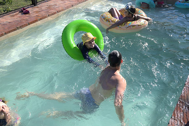 Brothers and sister are having fun in sea waves. Kids are jumping into incoming waves and laughing.\n\n