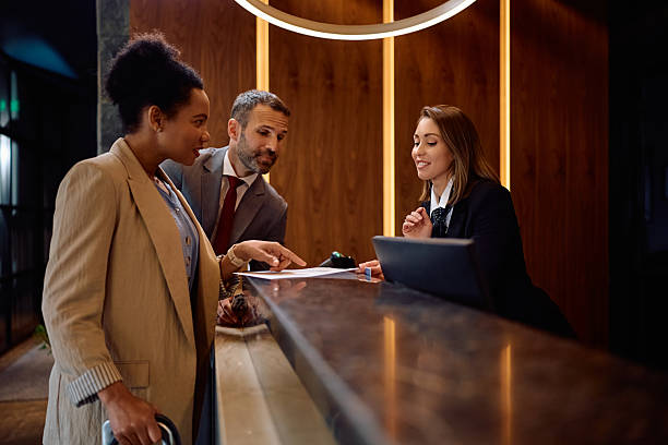 istock Happy business colleagues checking in at hotel reception desk. 2210276639