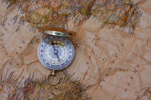 istock Antique brass compass resting on a world map, symbolizing travel and adventure. 2210276773