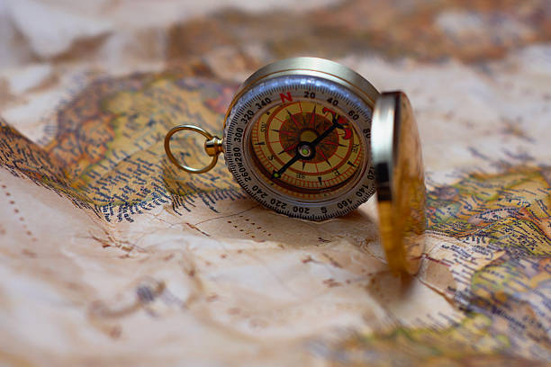 istock Antique brass compass resting on a world map, symbolizing travel and adventure. 2210276821