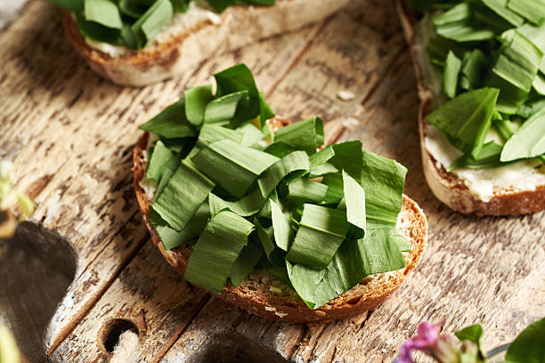 Chopped wild garlic leaves on a slice of bread on a wooden table