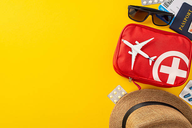 istock Travel essentials displayed including a red first aid kit, a passport, and accessories on a vibrant yellow background portraying preparedness, exploration, and journey safety 2210278815