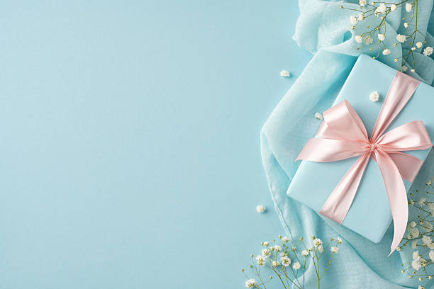 istock Beautifully wrapped light blue gift box with satin ribbon, accompanied by delicate floral accents 2210278830