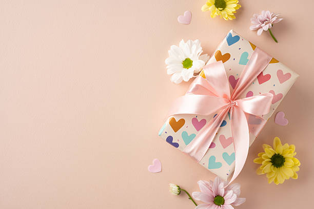 istock A decorated gift box with a delicate ribbon, surrounded by daisy flowers and scattered paper hearts, perfect for celebrations and Mother's Day 2210278833