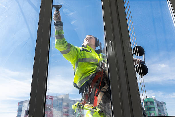 istock Professional Window Cleaner Performing His Job Safely While Suspended at Height, Showcasing the Importance of Safety Gear and Expertise in Window Washing Services 2210289135