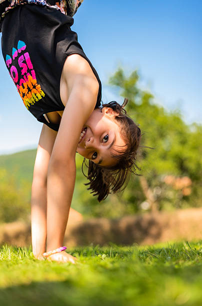 istock Happy kid having fun standing upside down on her hands on grass in the summer park. 2210289804
