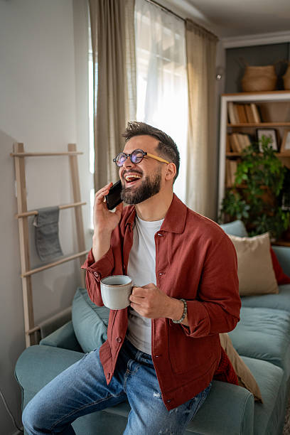 istock Happy man talking on the phone and drinking coffee at home 2210289917