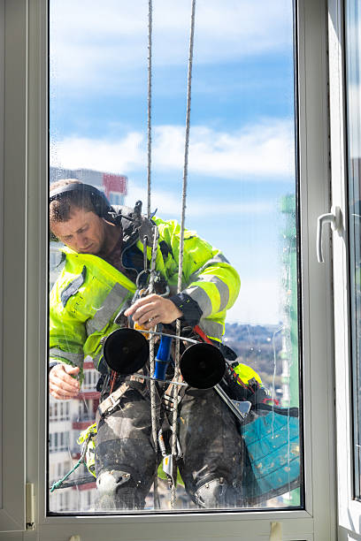 istock Professional Window Cleaner Performing High-Rise Building Maintenance While Harnessed, Ensuring Safety and Clarity with a Meticulously Cleaned Surface Under Bright Blue Skies 2210291176