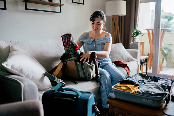 istock Woman packing clothes into suitcase on sofa preparing for a trip 2210298328