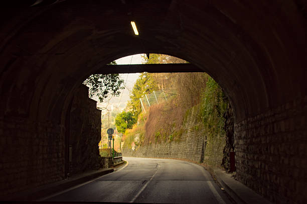 istock A narrow road passes through a dimly lit stone tunnel, with daylight visible at the exit. 2210299388