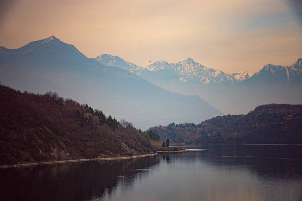 A misty morning view of Lake Como, with soft light illuminating the distant mountains.