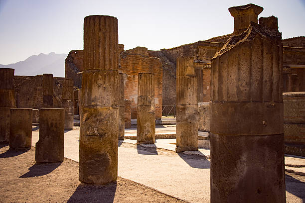 Sunlit ancient stone pillars in Pompeii archaeological site.