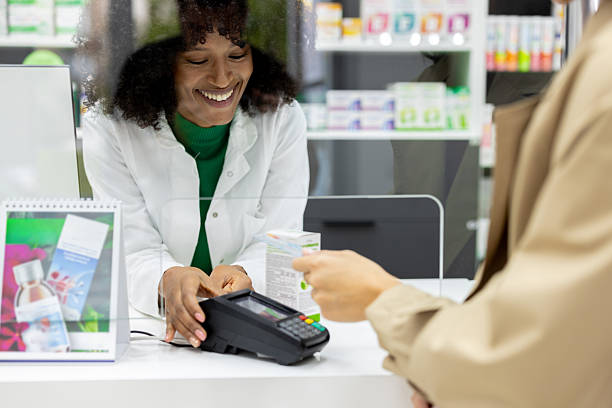 Young African pharmacist charging to a customer at her pharmacy