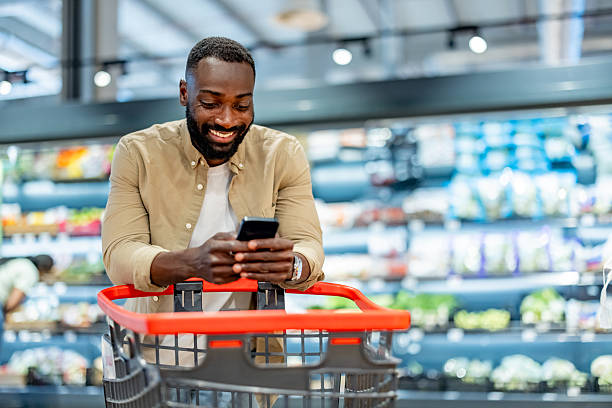 Smiling Man Using Smartphone While Shopping in Grocery Store