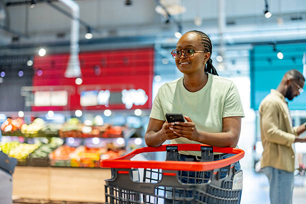 istock Woman Using Smartphone While Shopping in Grocery Store with Cart 2210300125