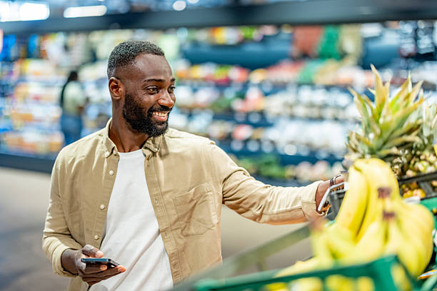 istock Smiling Man Shopping in Grocery Store While Holding Smartphone 2210300126