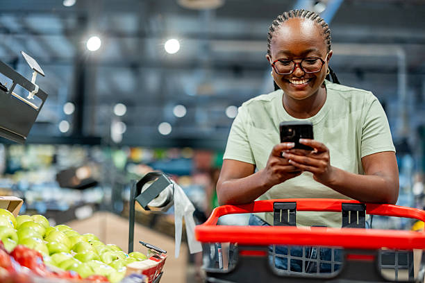 istock Woman Smiling While Using Smartphone in a Grocery Store 2210300128