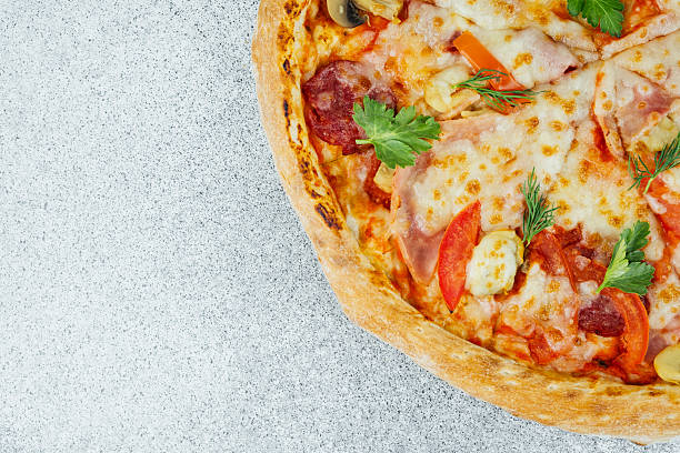 Freshly baked pizza featuring cheese, pepperoni, and colorful vegetables on counter.
