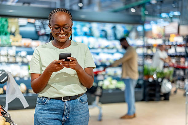 istock Woman Using Smartphone Inside Grocery Store While Shopping for Fresh Produce 2210302698