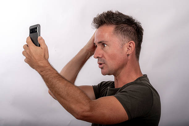 Young man checks his appearance on his phone.