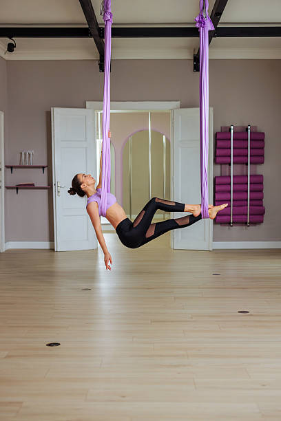 istock Young woman practicing aerial yoga using purple hammock in a studio 2210309817
