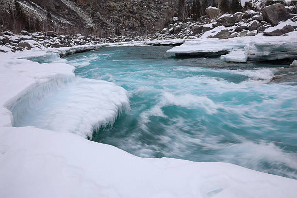 Wintertime with Chuya River in the Altai Republic. River flowing through snow covered rocks.