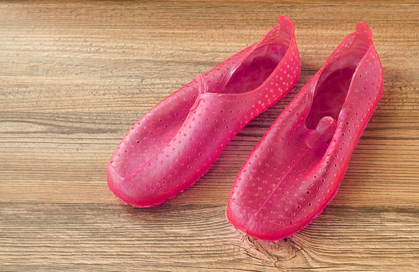 Above view of pink colored plastic gel water shoes on wooden surface