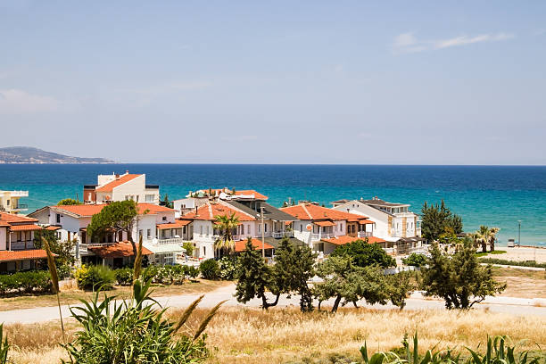 Long shot or remote view of by the sea, small summer houses with green trees