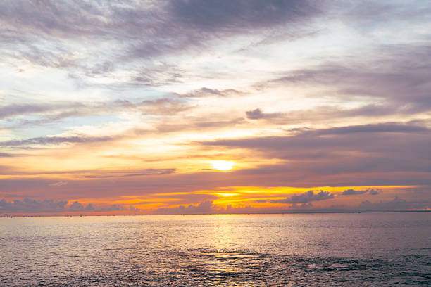 istock Beautiful twilight sky with dramatic orange clouds reflecting over serene sea at sunset. 2210321337