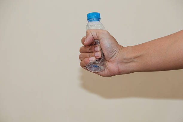 Close up of a man hand holding empty plastic water bottle on white background, recycling reduce reuse in zero waste concept.