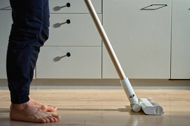 istock Barefoot man vacuuming floor with vacuum cleaner in modern kitchen 2210324523