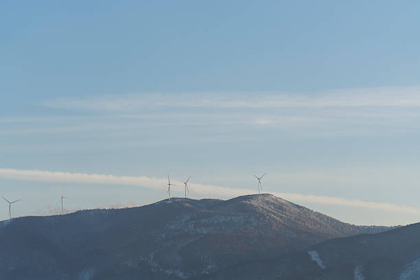 Wind turbine on snowy winter field. Alternative energy in cold weather. Aerial view of nature in Poland