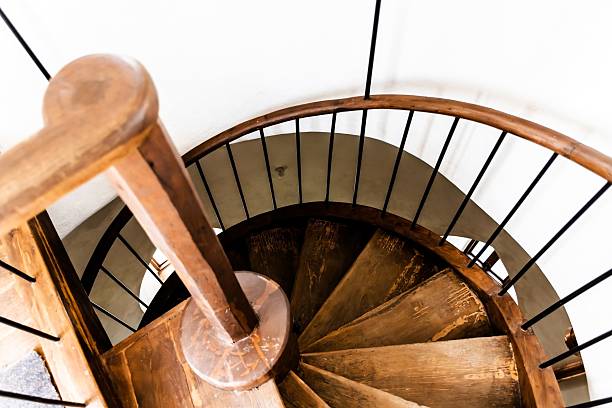 istock Wooden spiral staircase with white wall 2210332193