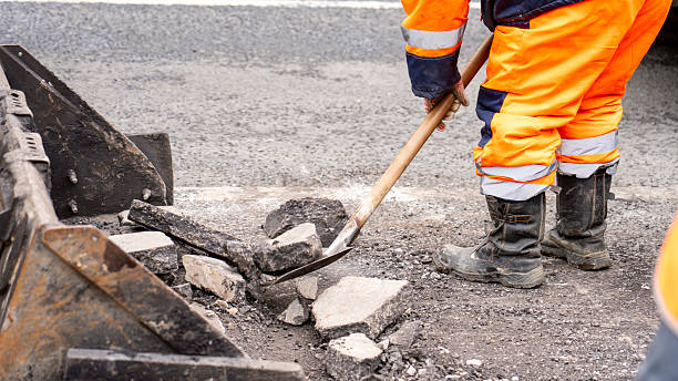 istock A man in an orange jumpsuit is using a shovel to clear a road 2210334621
